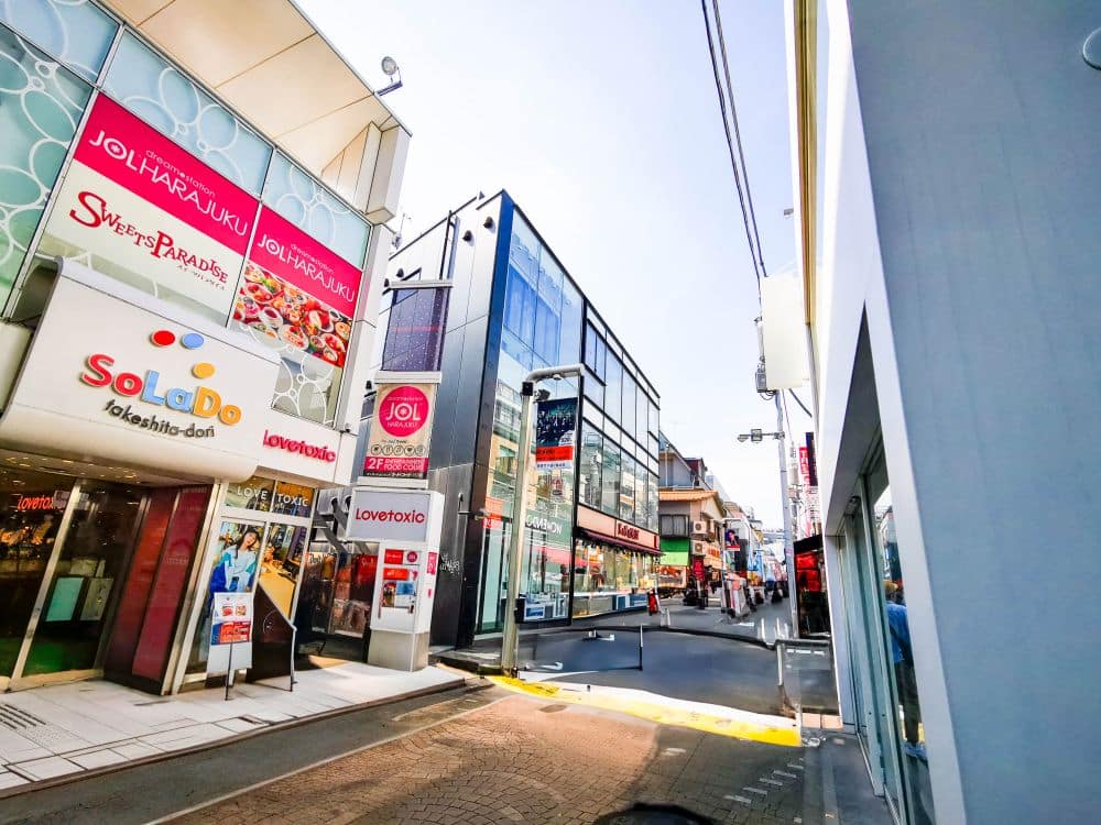 Eine lebhafte Straße in Harajuku mit vielen Gebäuden und bunten Schildern, die den lebendigen Geist der Takeshita Street einfangen.