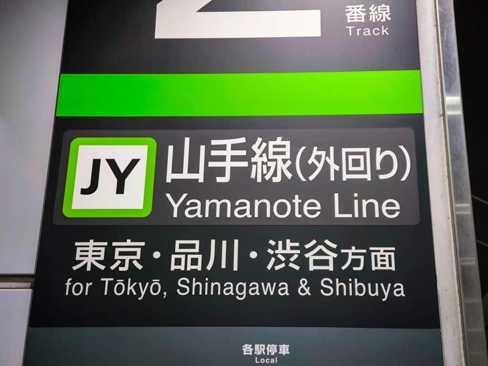 Ein Schild der Yamanote-Linie mit einem grünen Kreis und dem Code JY listet Ziele wie Tokio, Shinagawa und Shibuya auf. Es befindet sich an Gleis 2 und leitet Reisende effizient entlang dieser belebten Strecke.