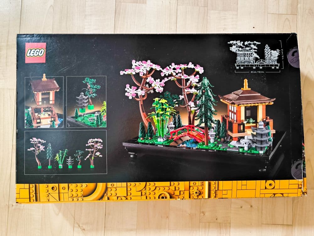 Die LEGO Set-Box zeigt eine detaillierte japanische Gartenszene mit Kirschblütenbäumen, einer roten Brücke, einem kleinen Tempel, Steinlaternen und üppigem Grün. Kleinere Bilder auf der linken Seite zeigen Nahaufnahmen und alternative Ansichten des Sets.