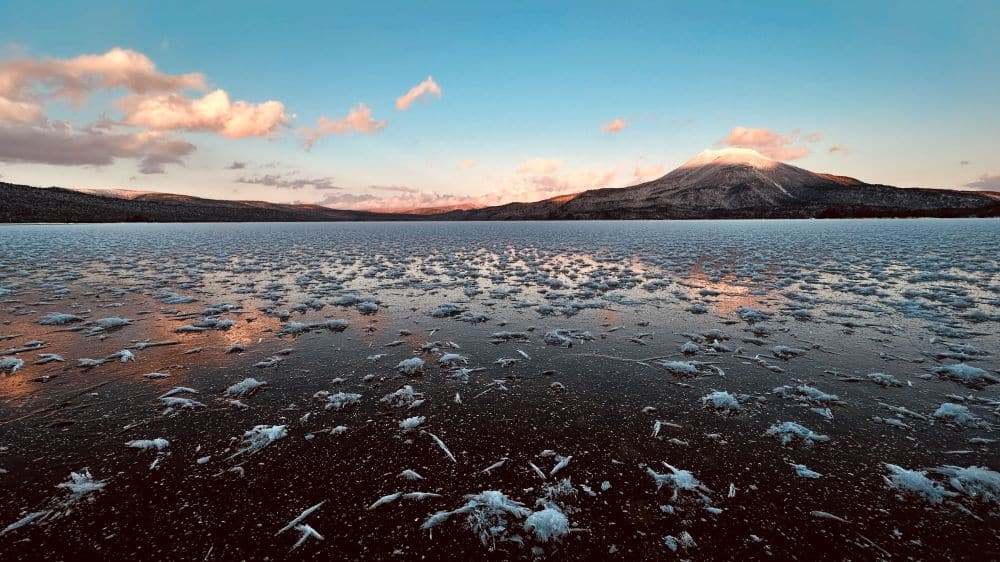 Ein zugefrorener See in einem malerischen Nationalpark mit einem hoch aufragenden Berg als atemberaubende Kulisse.
