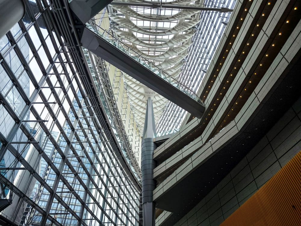 Das moderne architektonische Interieur ist vom Tokyo International Forum inspiriert und zeichnet sich durch dramatische Stahlträger, Glaswände und eine geometrische Decke mit geschichteten, gebogenen Elementen aus. Natürliches Licht durchflutet das geräumige Atrium und unterstreicht das elegante Design und die Struktur.